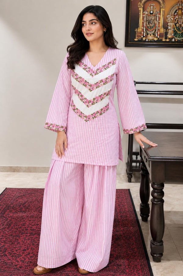 A soft pink striped suit set featuring traditional Farsi salwar bottoms, delicate floral chevron embroidery, and a relaxed silhouette that beautifully blends heritage craftsmanship with everyday comfort.