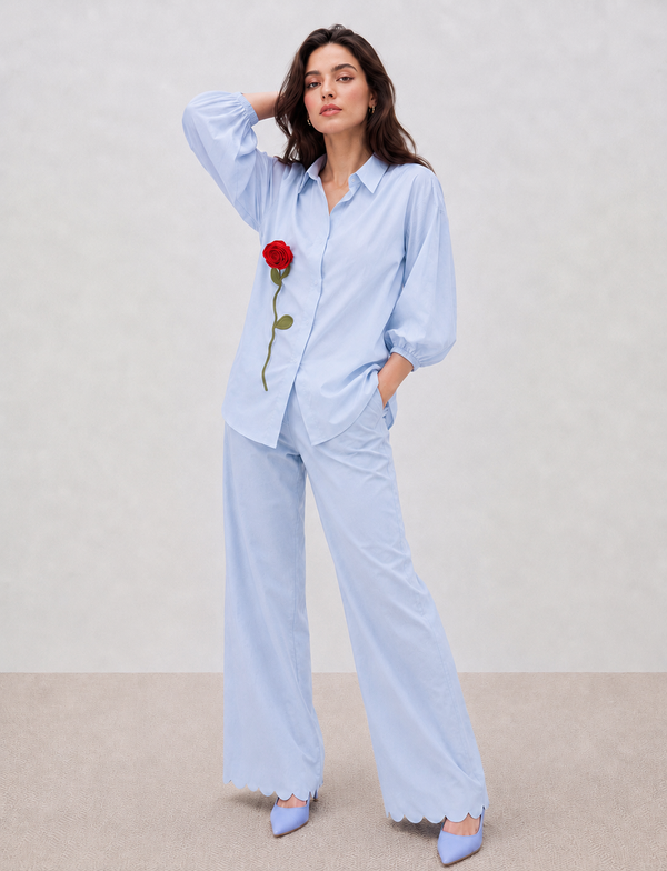 A relaxed powder-blue cotton co-ord set featuring handcrafted satin rose detailing, statement balloon sleeves, and signature scalloped hems for effortless everyday elegance.